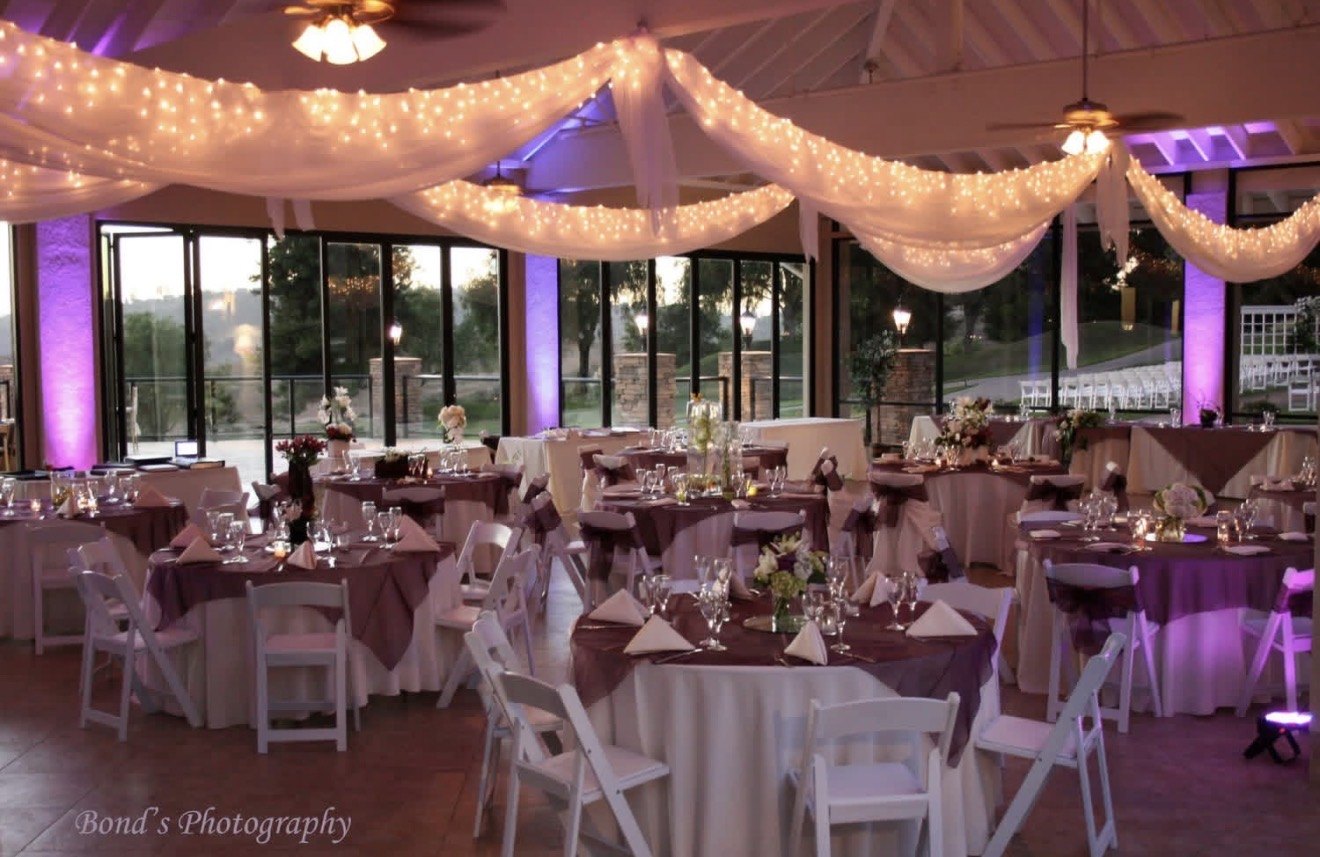 Reception hall with purple linens, string lights and purple uplighting