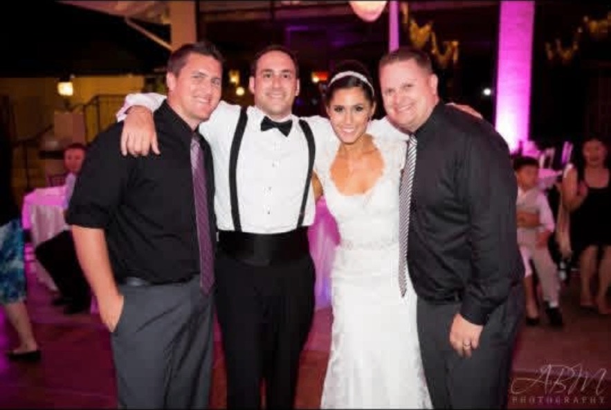 Bride and groom with friends on the dance floor under purple uplighting