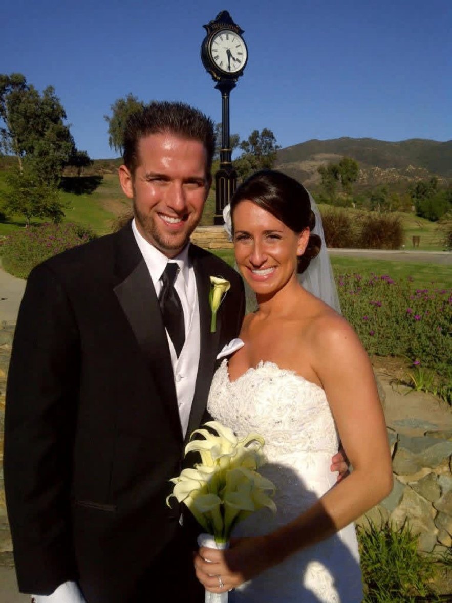 Bride and groom with calla lilies in front of a clock tower and hillside