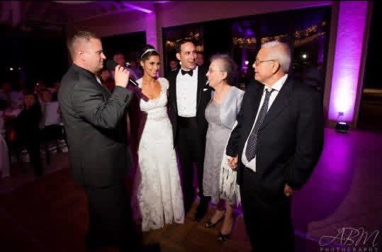 DJ Lennon Natter on the mic with the bride, groom and family at the reception