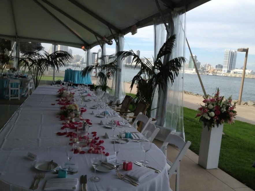 Waterfront tented reception table set with roses and a city skyline view