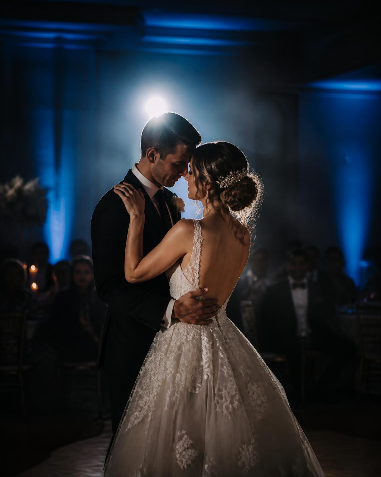 Bride and groom sharing their first dance under blue uplighting