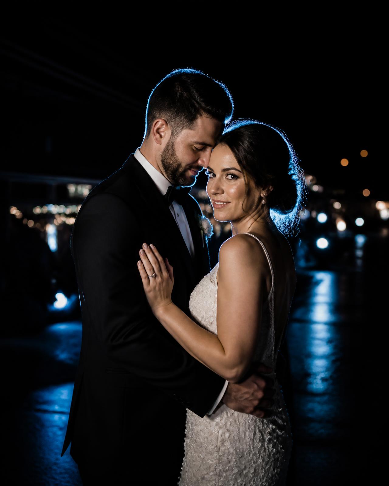 Night portrait of a bride and groom lit with cool blue rim light